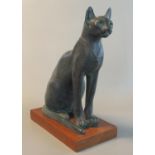 Heavy composition study of an Egyptian style seated black cat on a rectangular hard wood base. 35 cm