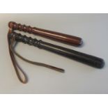 Two turned hardwood truncheons, one probably ebony. With leather wrist thongs. (2) (B.P. 21% + VAT)