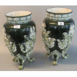Pair of Continental pottery relief decorated ovoid shaped vases, each on three scrolled feet,