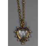 Victorian heart shaped locket pendant decorated with blue enamel and surrounded by pearls. On yellow