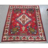 Middle Eastern design carpet on red ground with multicoloured stylised flowers and foliage and