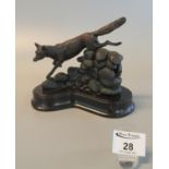 Modern patinated bronze sculpture of a fox leaping a stone wall on shaped wooden base. A