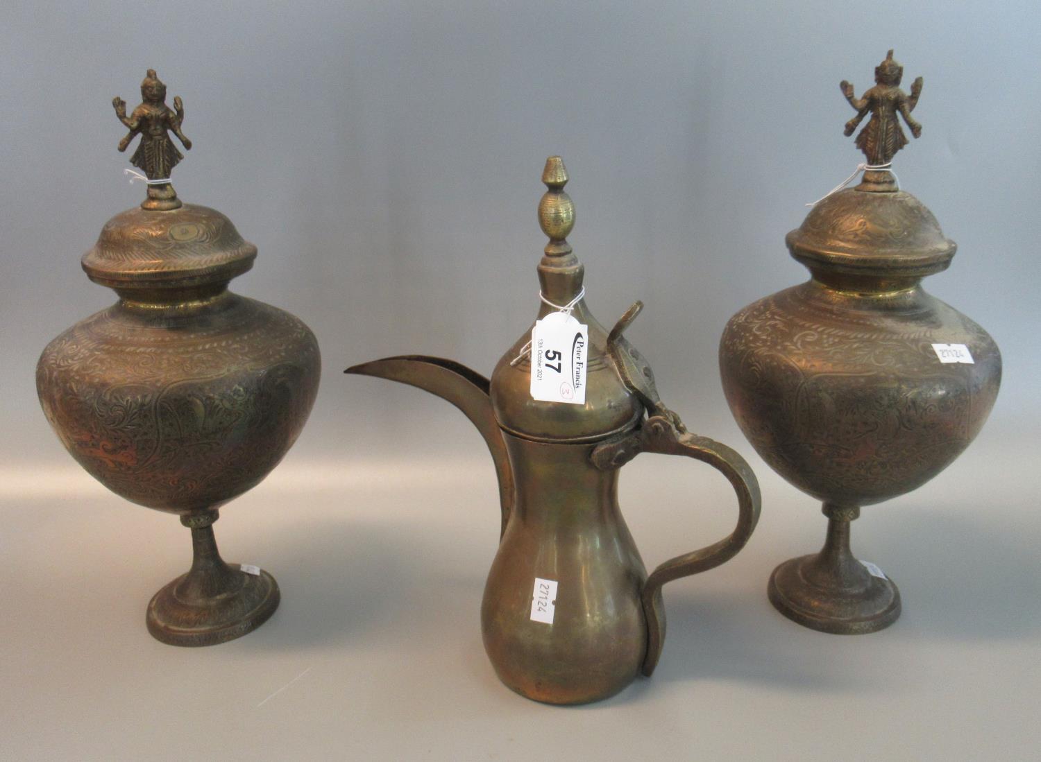 Pair of brass Indian style lidded pedestal urns with deity finials, together with a brass dallah. (