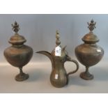 Pair of brass Indian style lidded pedestal urns with deity finials, together with a brass dallah. (