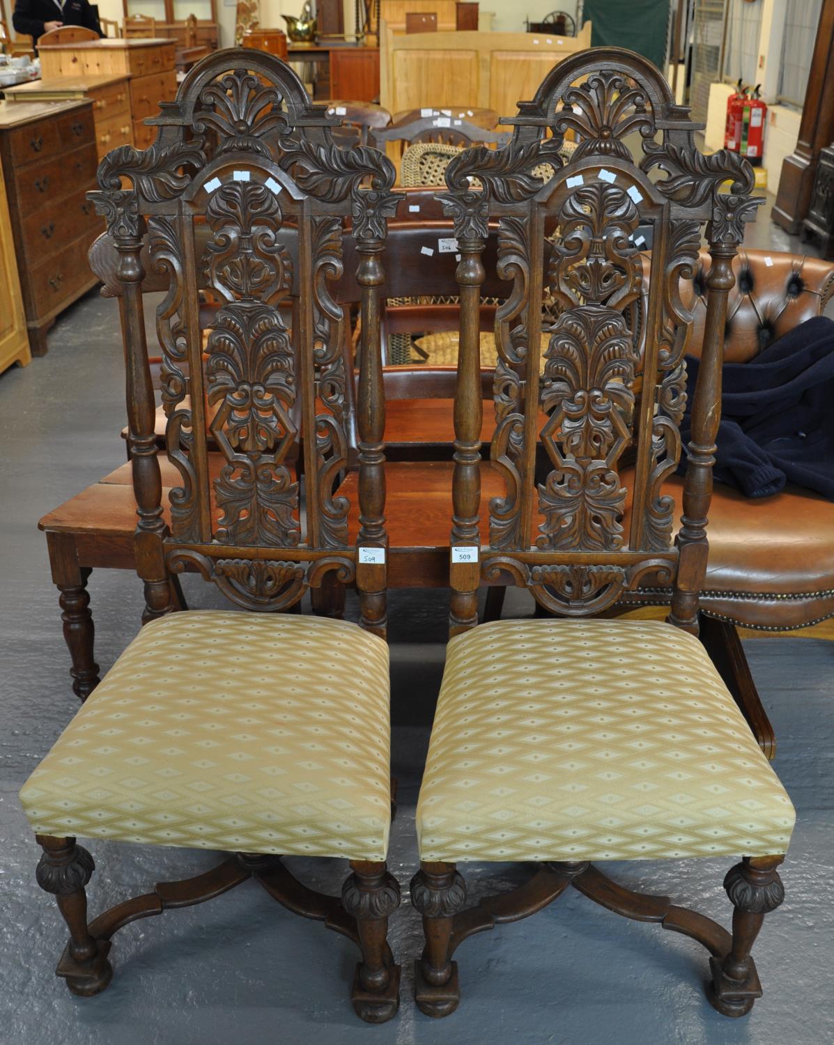 A pair of 20th Century heavily carved high back hall chairs with stuff over seats, standing on