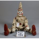 A clown peg doll with painted face and printed cotton outfit, possibly by the Schoenhut company. (