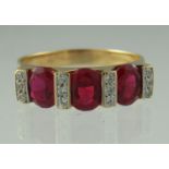 An 18ct gold three stone ruby and diamond ring. The three oval rubies separated by three rows of