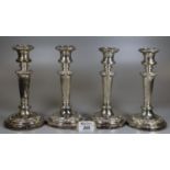 Two pairs of Victorian silver candlesticks with repousse bands, loaded bases and armorials. 21cm