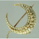 Pearl set crescent brooch with pearl set floral wreath detail. Set in yellow metal. Diameter 32mm.