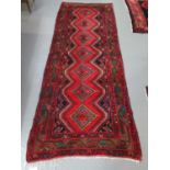 Middle Eastern design Hamedan runner on a red ground with central lozenge medallions decorated