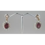 A pair of oval ruby and diamond drop earrings set in 9ct gold. Length of drop 21mm. Drop approx 14 x