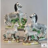 Two pairs of 19th Century Staffordshire pottery zebra, 22 and 15cm high approx, on naturalistic