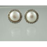 A pair of cultured pearl and diamond earrings. The half pearls surrounded by rose cut diamonds.