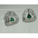 A pair of heart shaped emerald and diamond earrings, the heart shaped emerald surrounded by baguette