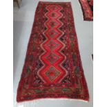 Middle Eastern design Hamadan runner on a red ground with central lozenge medallions decorated