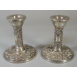 Pair of silver dressing table candlesticks, repousse decorated with exotic birds and foliage.