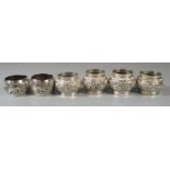 Set of four white metal napkin rings, together with a pair of white metal napkin rings decorated