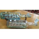 Two ships in bottles, small wooden models in sealed glass bottles, one of which has a wooden