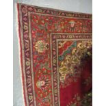 Middle Eastern design Tabriz carpet on a red ground, the borders with multi-coloured geometric