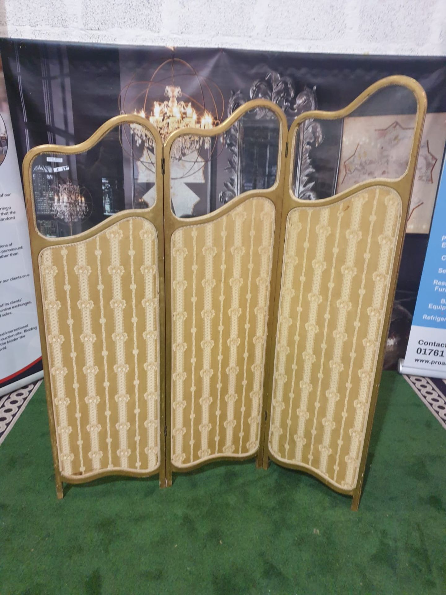 A giltwood and upholstered screen.The three graduated panels with glazed upper panels over damask-