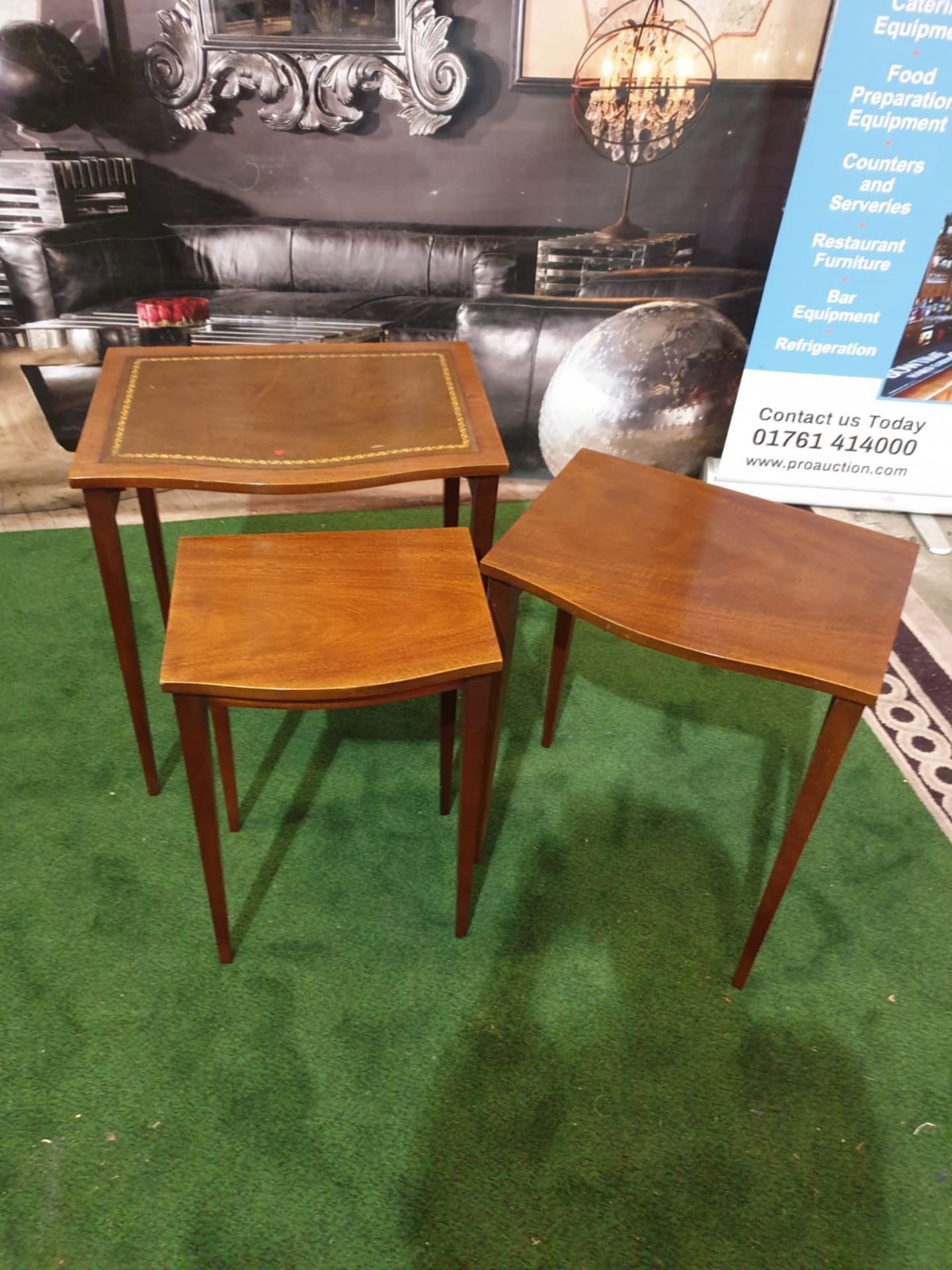 A nest of three mahogany bow front tables in the George III style. The largest table with a gilt