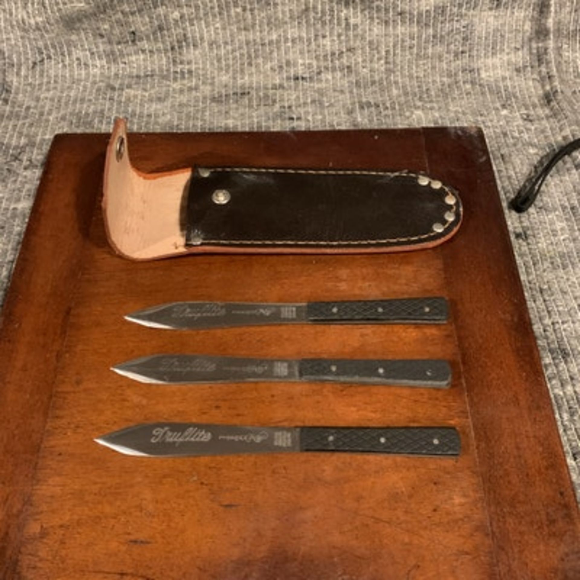 A set of three English stainless steel throwing knives in leather folding case of typical shape