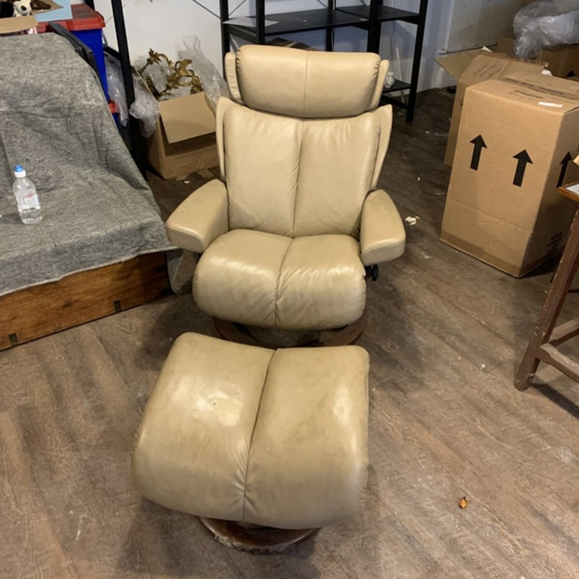 An Ekornes `Stressless` leather covered adjustable chair and stool, Norway. The pale caramel brown