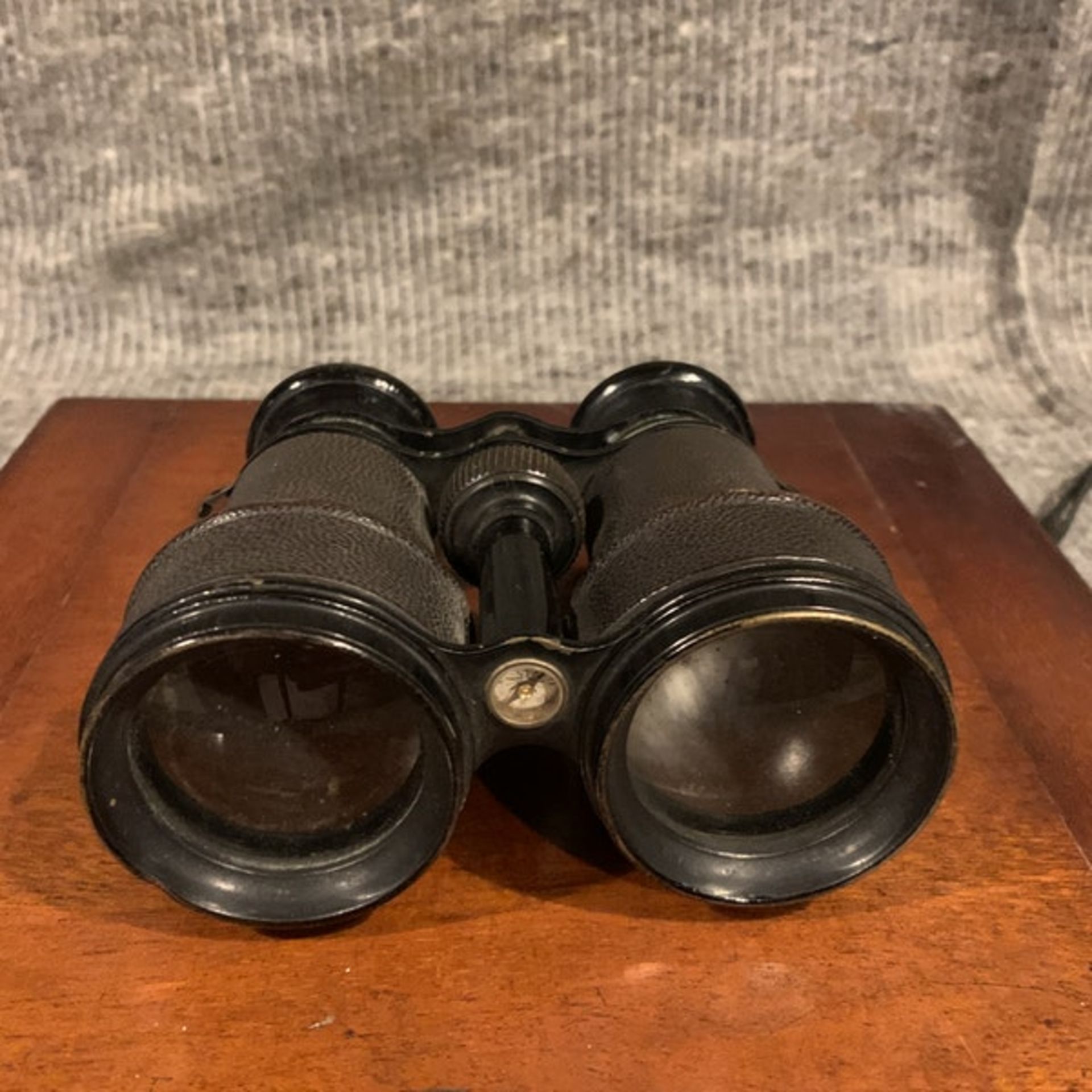 A Pair of vintage binoculars with black leather covered casing and black enamel trim, a compass is