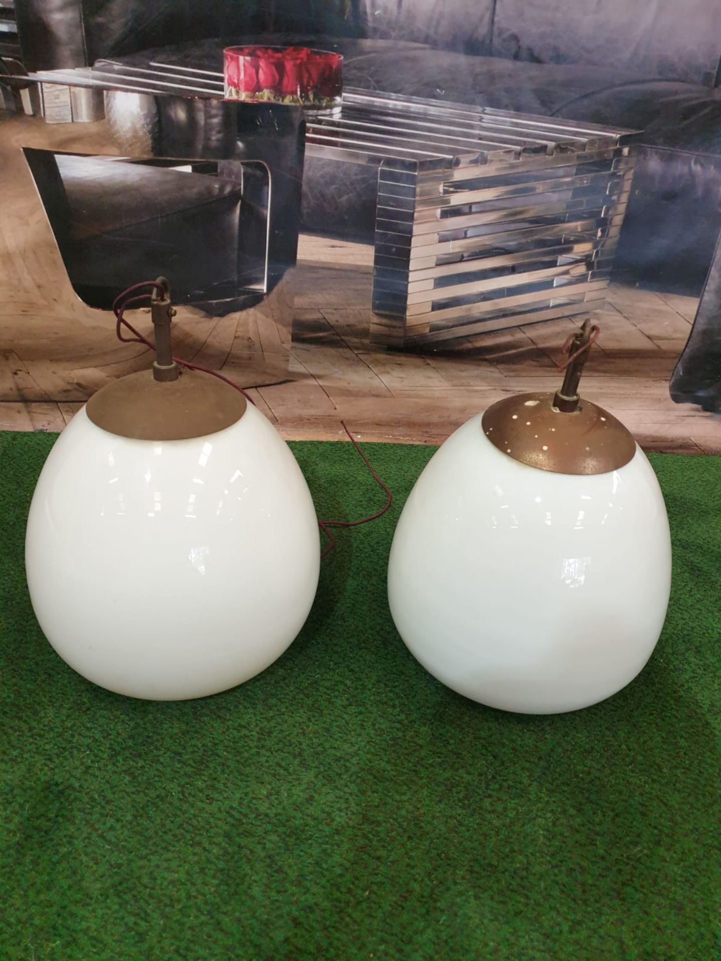 A pair of white glass and metal mounted pendant lights.Of ovoid form and with copper caps and