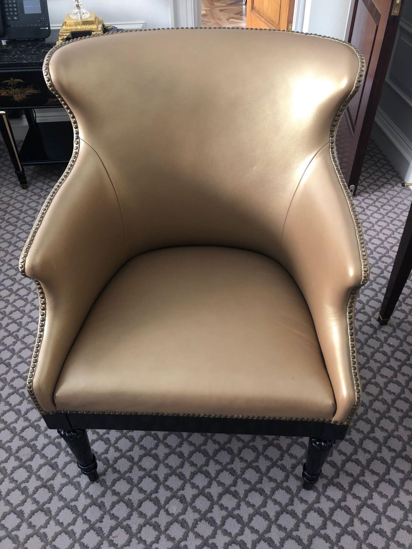 A Modern Wing Back Chair Upholstered In Gold Leather With Pin Stud Detail On Dark Solid Wood Frame