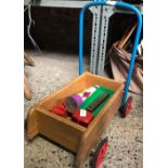 CHILD'S WOODEN 4 WHEELED PUSH CART WITH A KALEIDOSCOPE, HARMONICA, PLASTIC TRUCK & WOODEN CAR