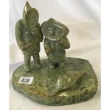 A GREEN SOAPSTONE INUIT CARVING ON BASE WITH 2 FIGURES & A SEAL