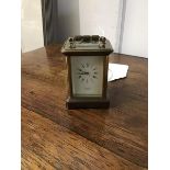 A miniature brass four glass carriage clock with white enamel dial and roman numerals, marked