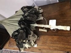 An Edwardian lady's ivory handled green silk parasol with black and white lace trim and interior,