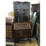 A 1920s oak two part bureau bookcase, the top with two arched astragal glazed doors enclosing a