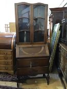 A 1920s oak two part bureau bookcase, the top with two arched astragal glazed doors enclosing a