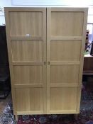 A Habitat Radius oak two door wardrobe, the panelled doors enclosing a single hanging rail, with