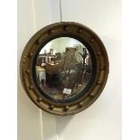 An early 20thc convex wall mirror in reeded ebonised slip and gilded frame with applied sphere