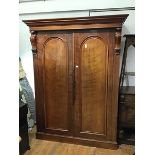 A 19thc plum pudding mahogany two door wardrobe, the moulded cornice and plain frieze above a pair