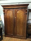 A 19thc plum pudding mahogany two door wardrobe, the moulded cornice and plain frieze above a pair