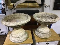 A pair of composite bird baths/shallow urns, with circular tops with gadrooned edges, on waisted