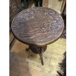 A Japanese carved table, the circular top in relief with monkeys, resting at the foot of a tree,