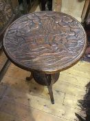 A Japanese carved table, the circular top in relief with monkeys, resting at the foot of a tree,