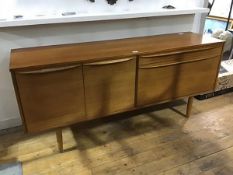 A 1960's teak sideboard, the rectangular top with two cupboard doors, enclosing a single shelf,