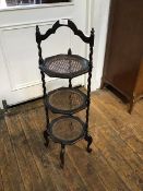 An unusual oak three tier cakestand with inset canework panels and shaped handle to top, raised on