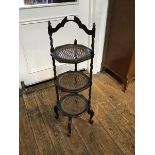 An unusual oak three tier cakestand with inset canework panels and shaped handle to top, raised on