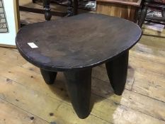 A carved African hardwood Senufo (Ivory Coast) stool/low table, the oval top on four substantial