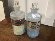 Two clear glass chemist's jars with glass labels, Eau de Cologne and Tinct.card.co., complete with