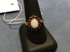 A 9ct gold opal and garnet ring, the oval opal with a surround of garnets (T) (3.6g)