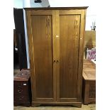 An oak wardrobe, the plain moulded top above two panel doors, enclosing shelves and hanging rail, on